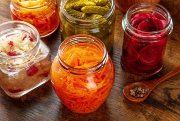 Fermented food. Canned vegetables. Pickled carrot, beet, sauerkraut and other organic preserves in mason jars. Healthy vegan products on a wooden table